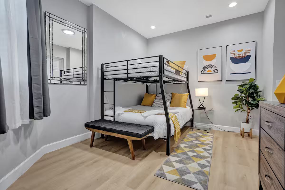 Conquer Mastermind Modern bedroom with a metal bunk bed, geometric decor, a patterned rug, and stylish touches—perfect for relaxing after a productive Marketing or Conquer Mastermind session. Video Agency Owner Mastermind